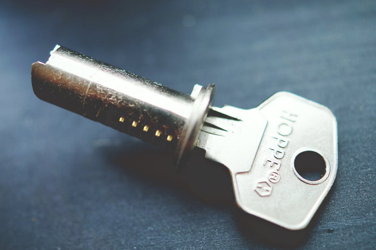 Detailed close-up image of a metallic key with lock cylinder on a dark surface, highlighting intricate details.